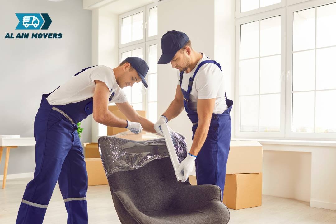 Al Ain Movers staff wrapping a chair in a bright room.